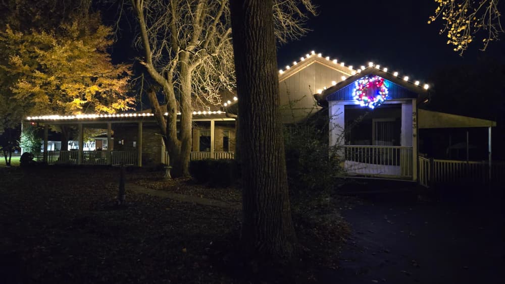Warm white roofline lights and a lit wreath on a covered porch home