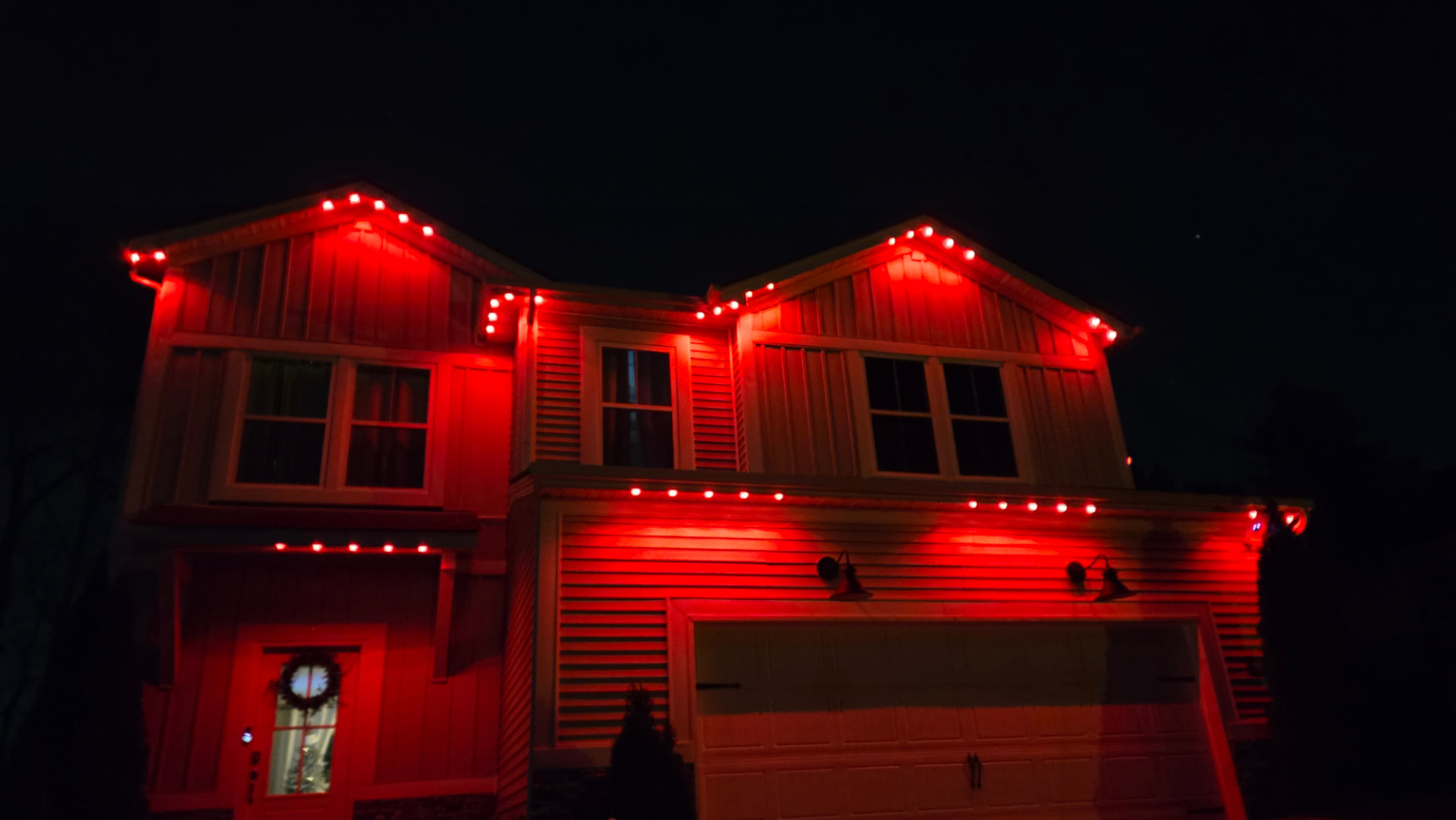 Craftsman-style home at night with permanent roofline lighting set to solid red