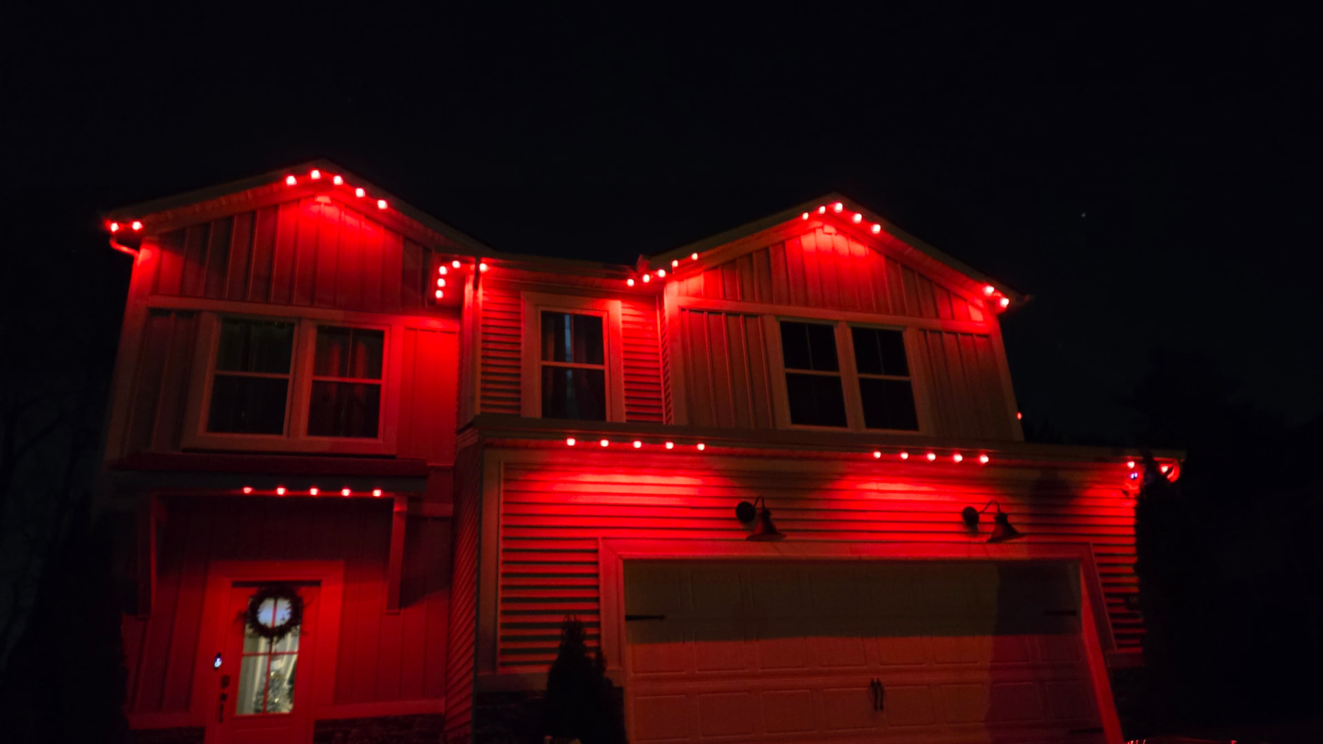 Front elevation of a home lit in red from permanent eave-mounted LEDs